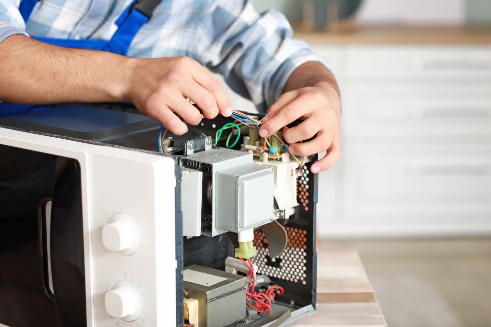 Worker repairing microwave oven in kitchen, closeup Microwave Repair