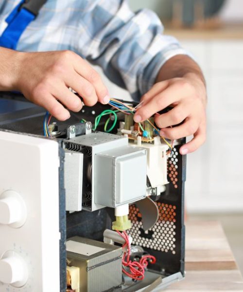Worker repairing microwave oven in kitchen, closeup