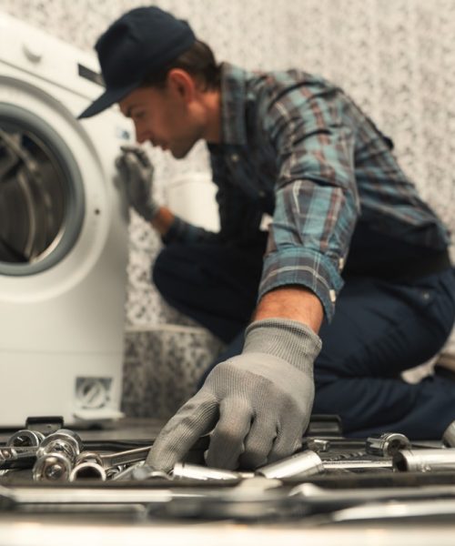 choosing-the-right-tool-plumber-repairing-washing-machine-picture-id1170038003